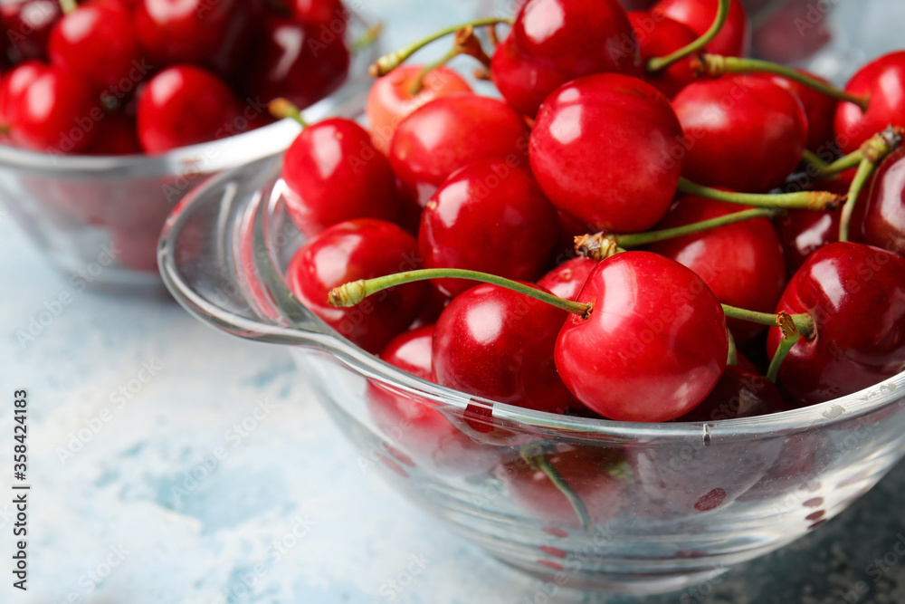 Glassware with sweet cherry on color background, closeup