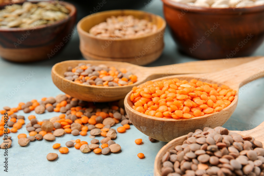 Spoons with lentils on color background, closeup