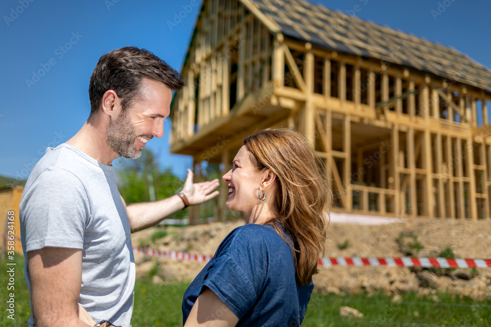 Couple looking at their new house under construction, planning future and dreaming