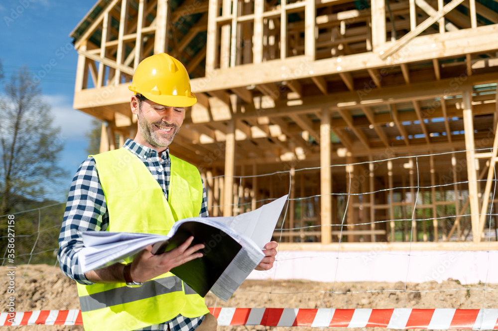 Architect on building site looking at blue prints house plans