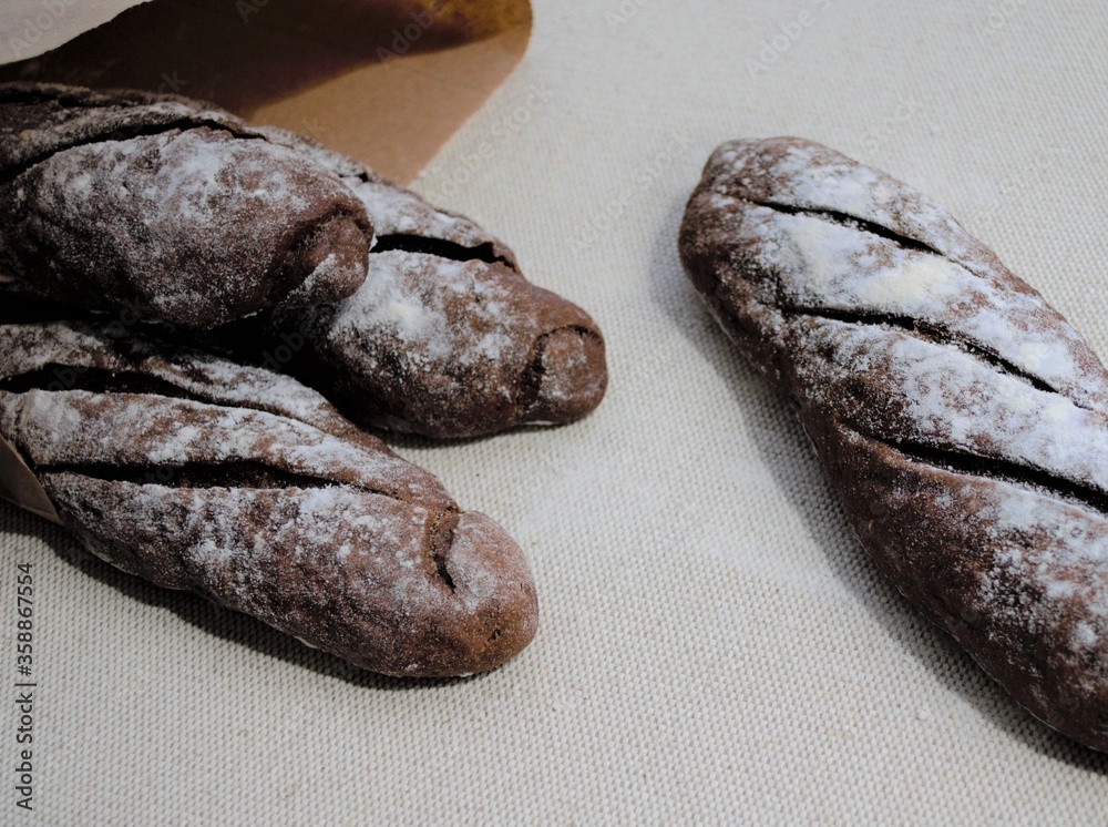 Composition of homemade French rye baguettes in the rays of the day sun, three pieces in a craft bag