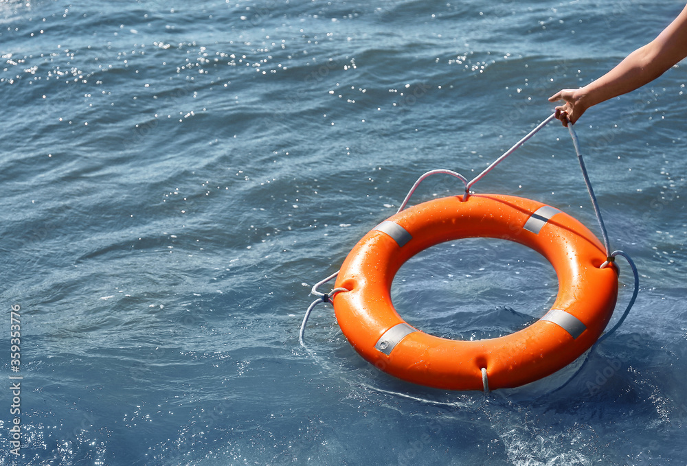 Woman throwing lifebuoy ring on water