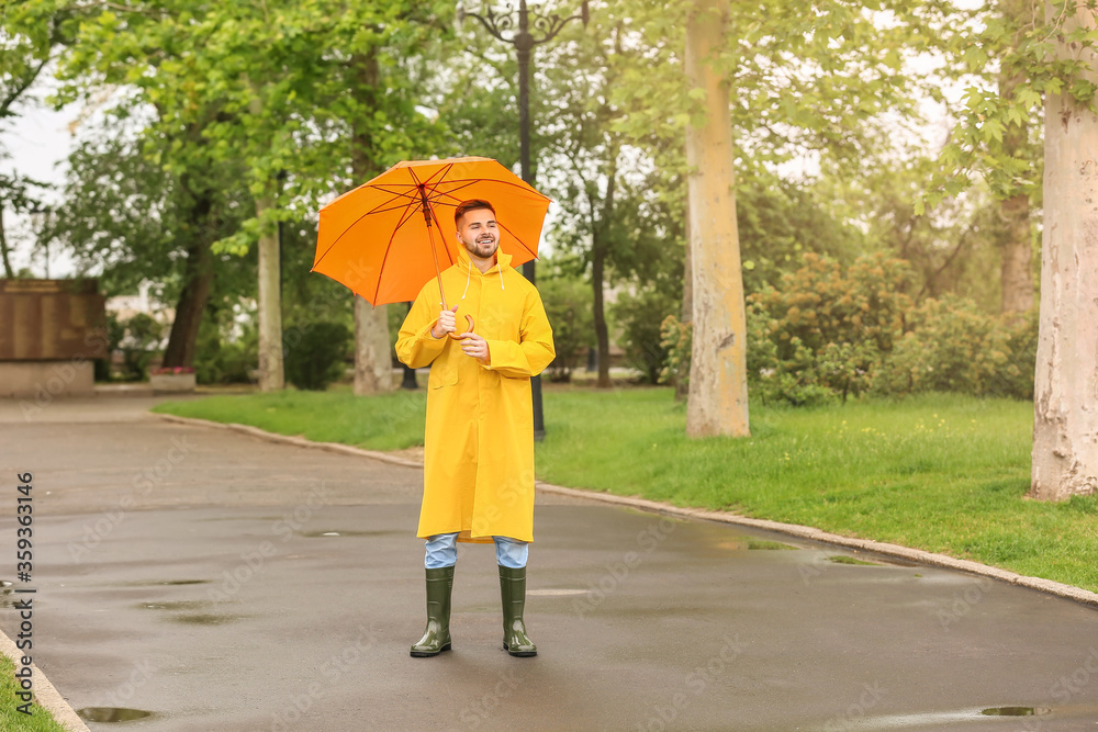 年轻人在户外打着雨伞，穿着雨衣