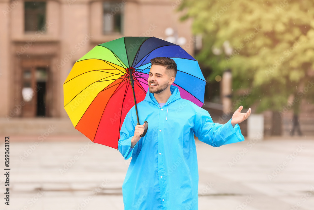 年轻人在户外打着雨伞，穿着雨衣