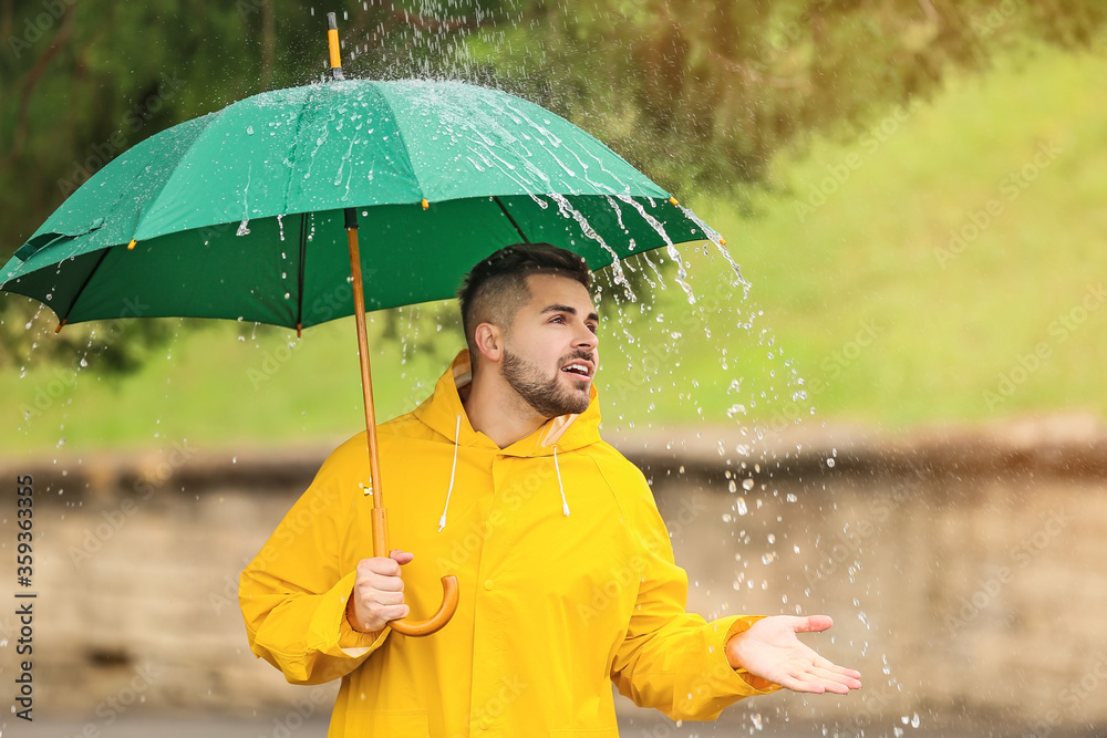 年轻人在户外打着雨伞，穿着雨衣