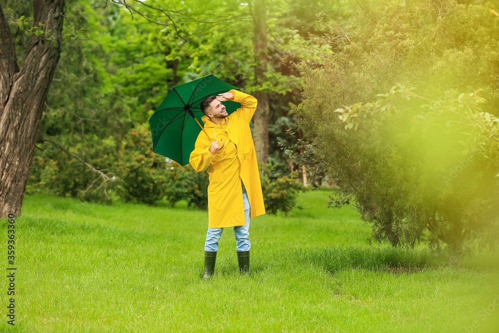 年轻人在户外打着雨伞，穿着雨衣