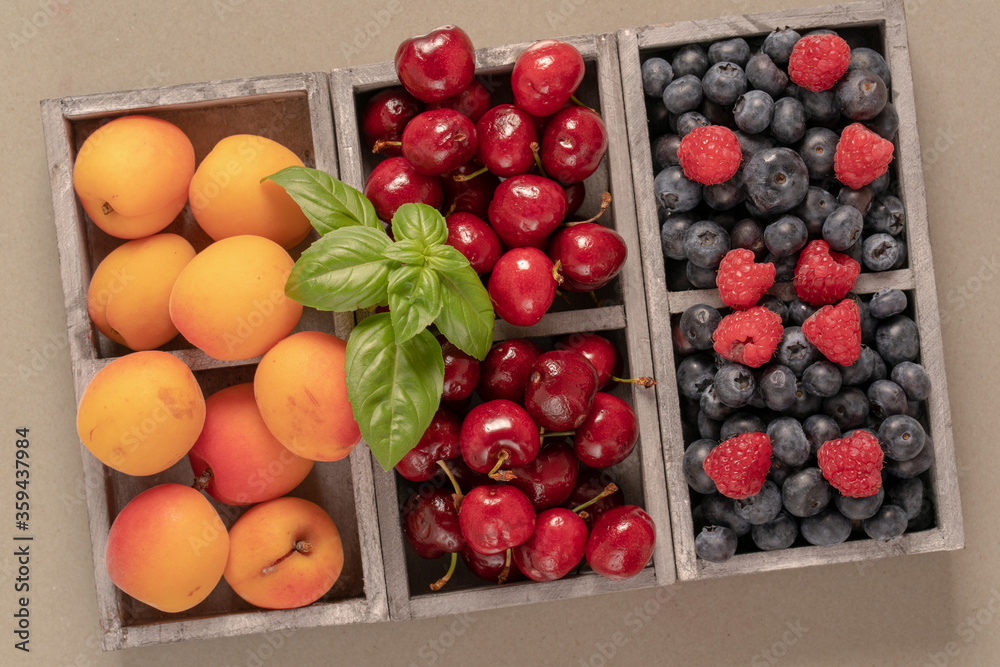 blueberries, cherries and peaches in a wooden box.