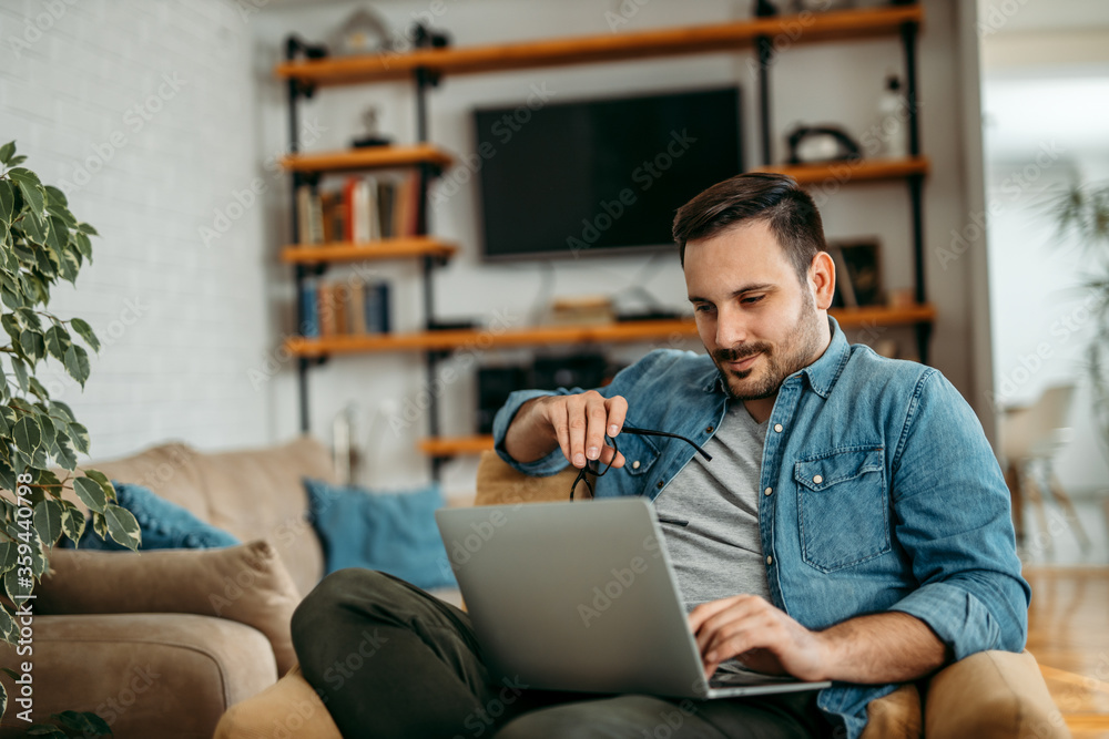 Charming man using laptop at home, portrait.