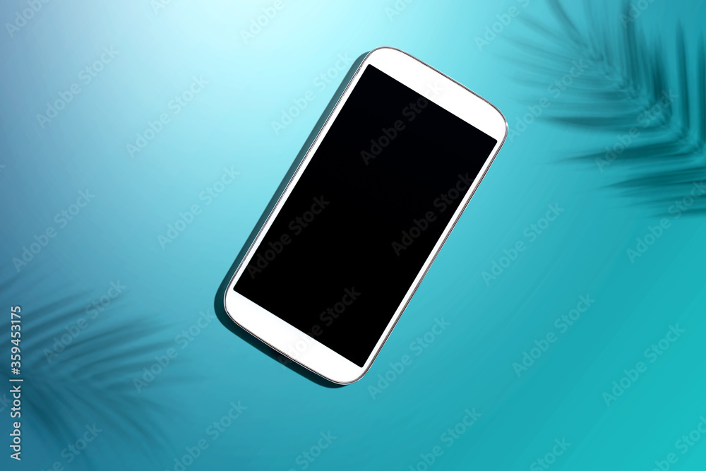 Smartphone with tropical palm leaves and shadow - flat lay