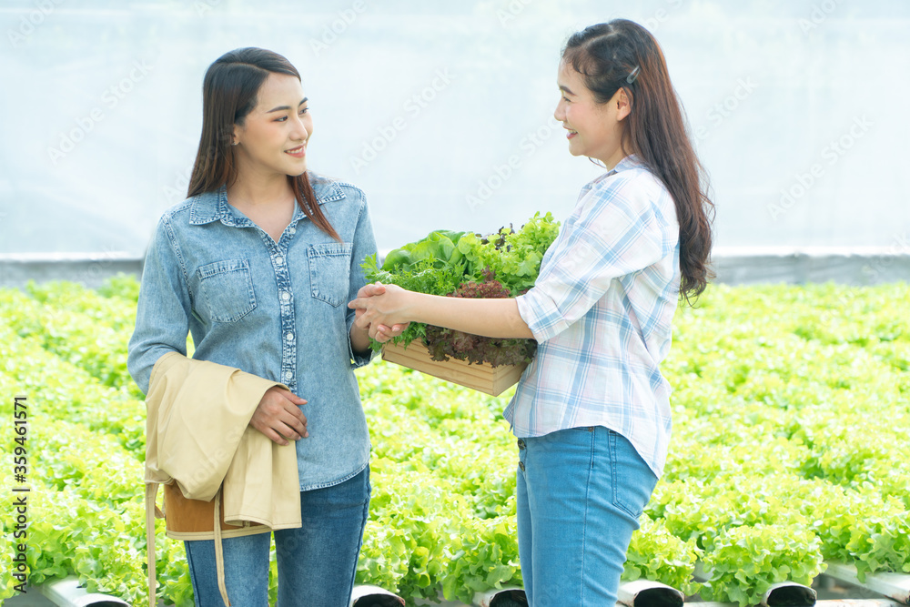 协议成功后，亚洲女农民拿着菜篮子与伙伴握手