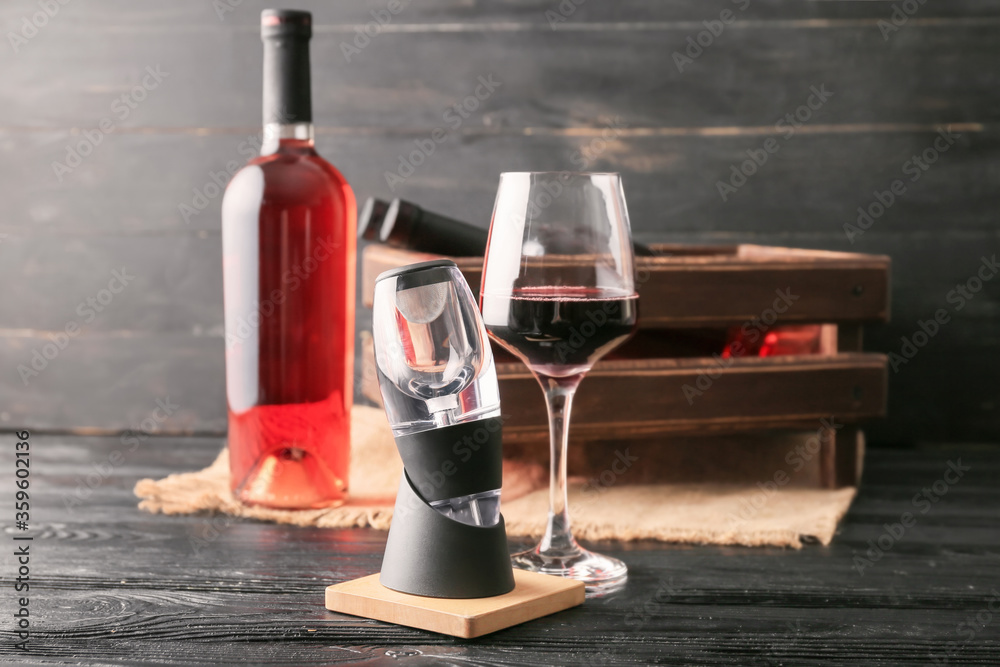 Aerator with glass of wine and bottle on table