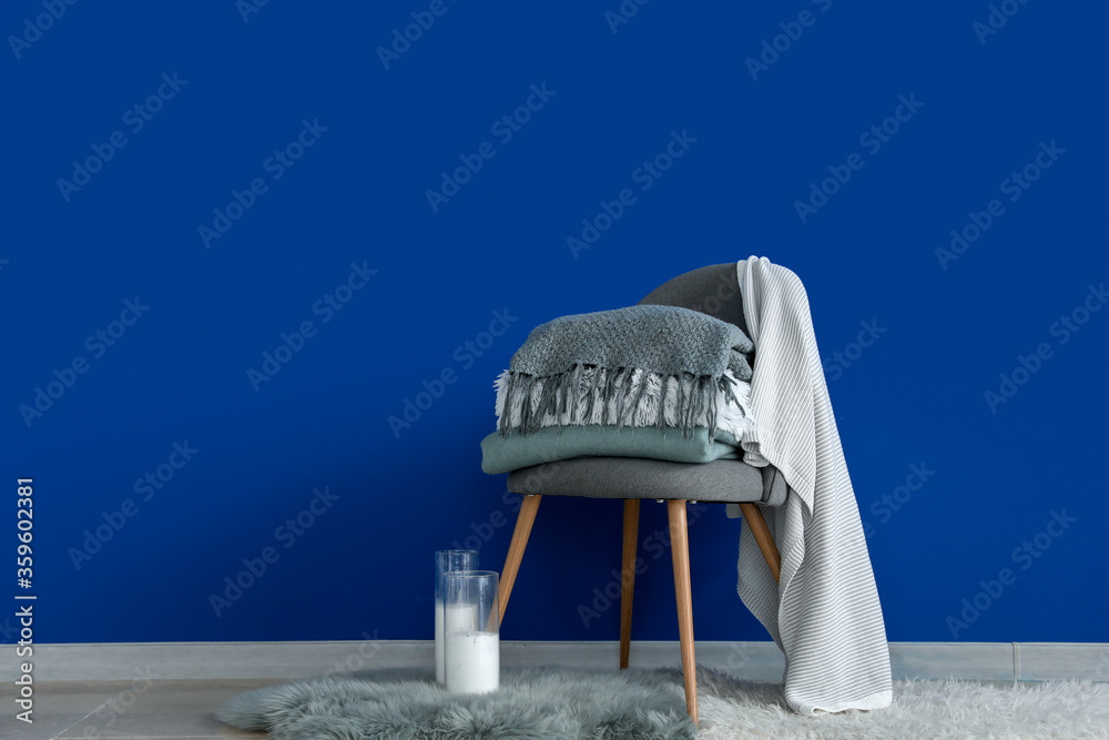 Chair with plaids and aroma candles near color wall