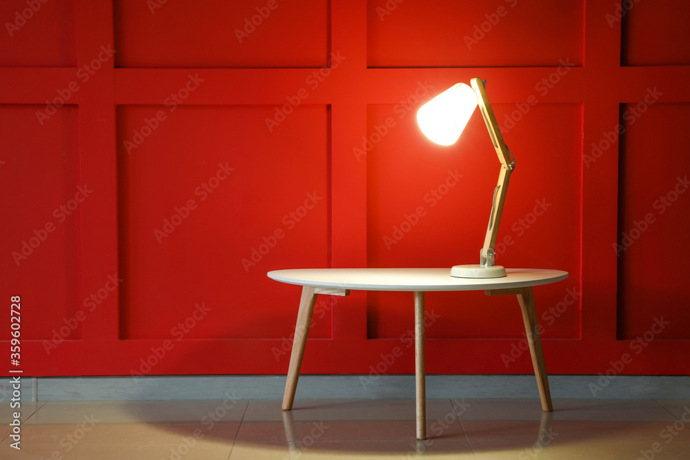 Glowing lamp on table in dark room