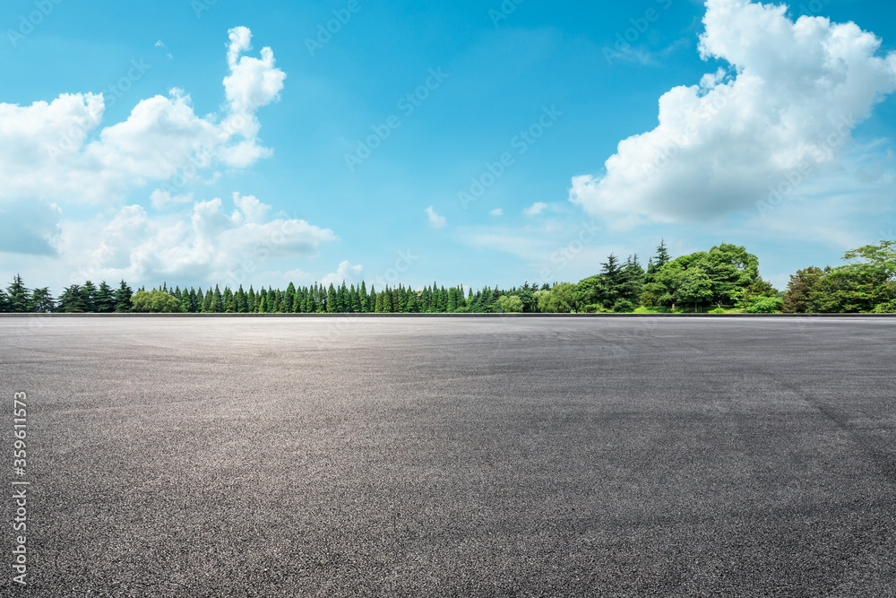 空旷的柏油路和蓝天下的绿色森林。