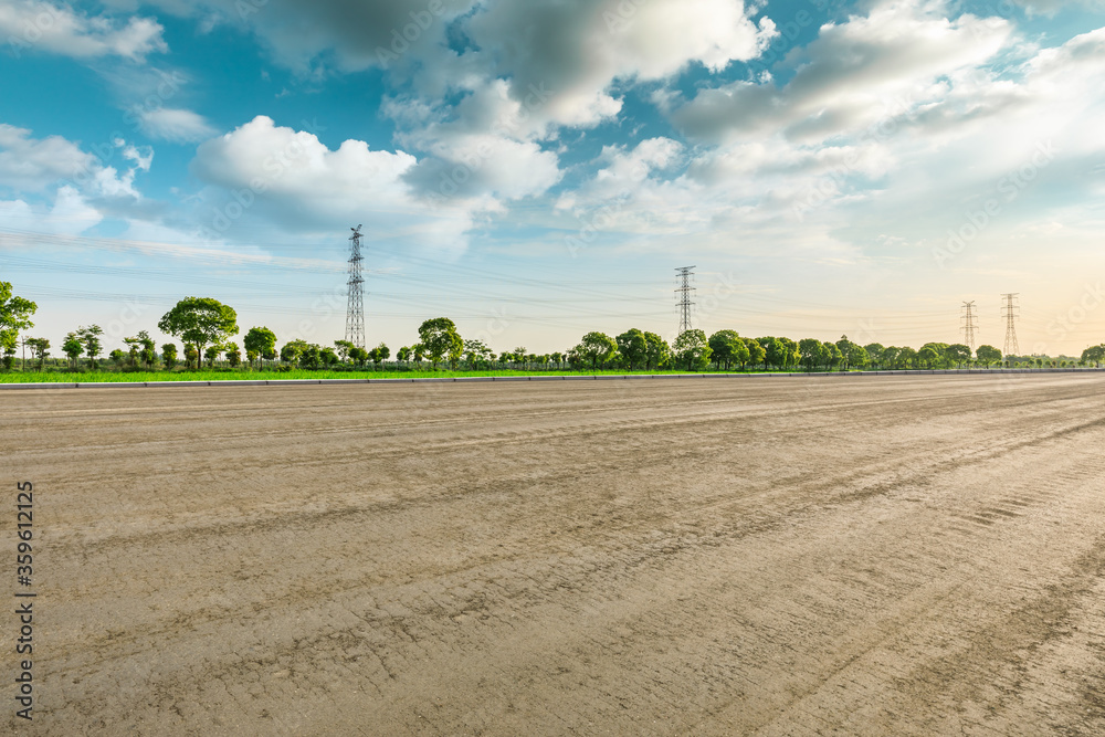 Rural dirt road ground and green forest in a sunny day.