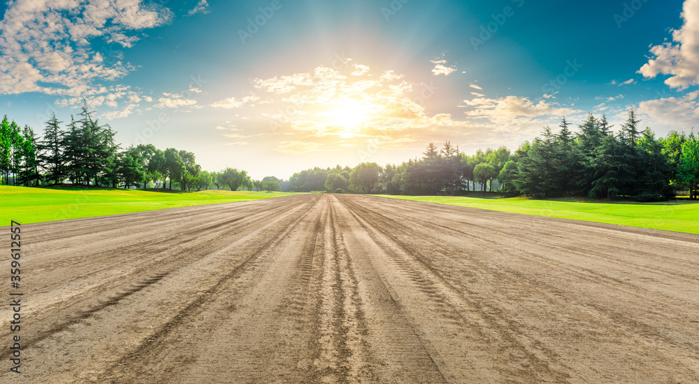 Rural dirt road ground and green forest at sunrise.