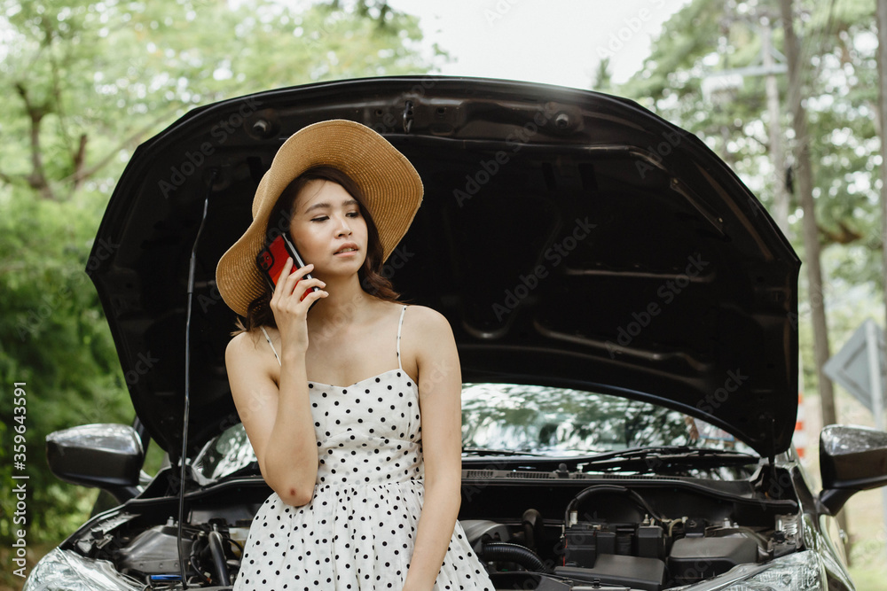 A young Asian tourist is talking on the phone to call her car insurance company to check the conditi