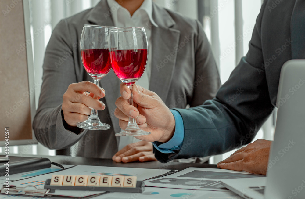 Two businessmen are sipping wine in the office, working to celebrate the success of the company busi