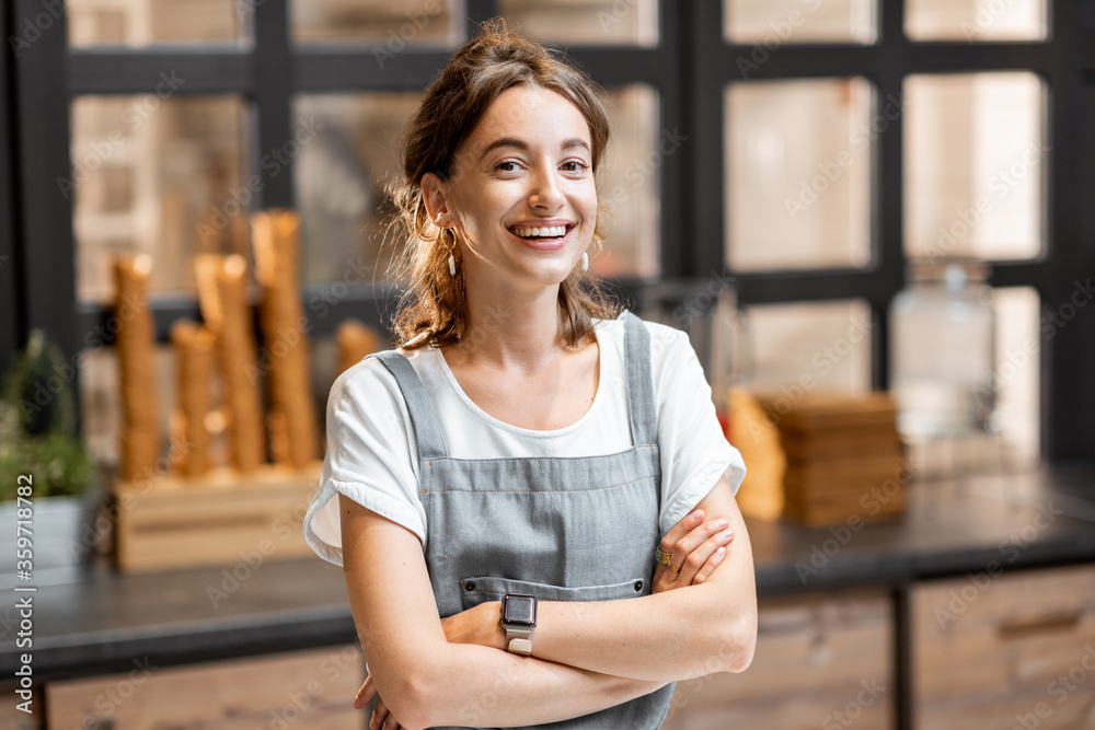 Portrait of a young and happy saleswoman at the counter in ice cream shop or cafe. Concept of a smal