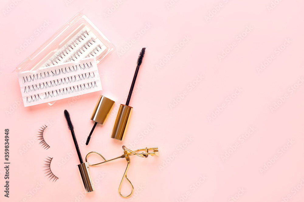 Mascara, eyelash extensions and curler on color background