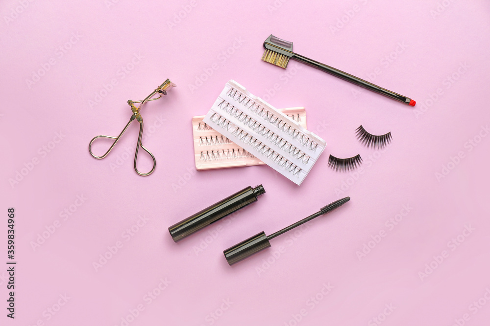 Mascara, eyelash extensions, curler and brush on color background