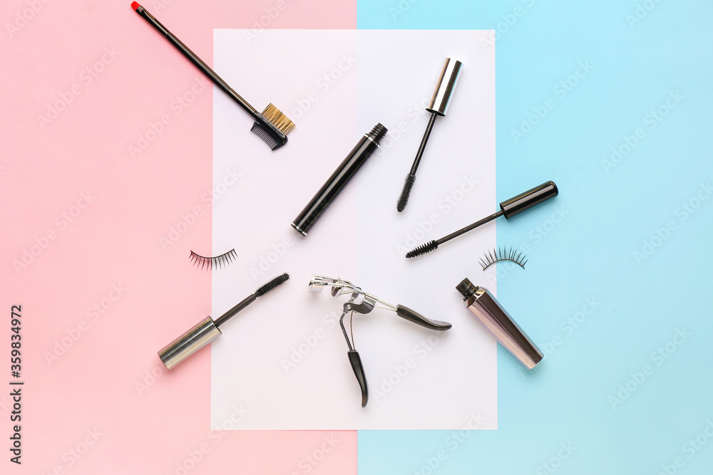 Black mascara, fake eyelashes, brush and curler on color background