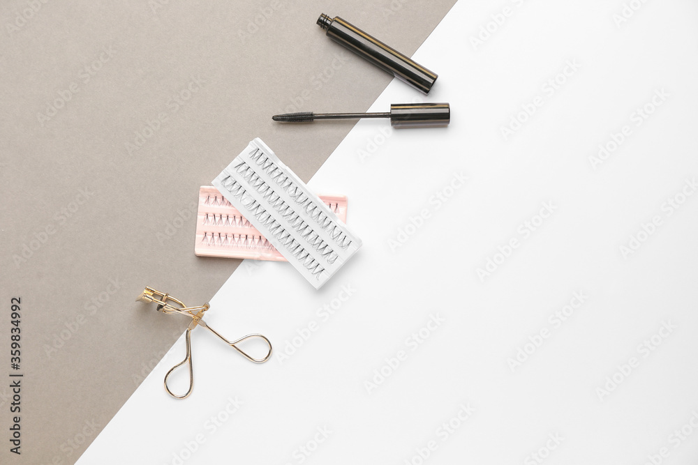 Mascara, eyelash extensions and curler on white and grey background