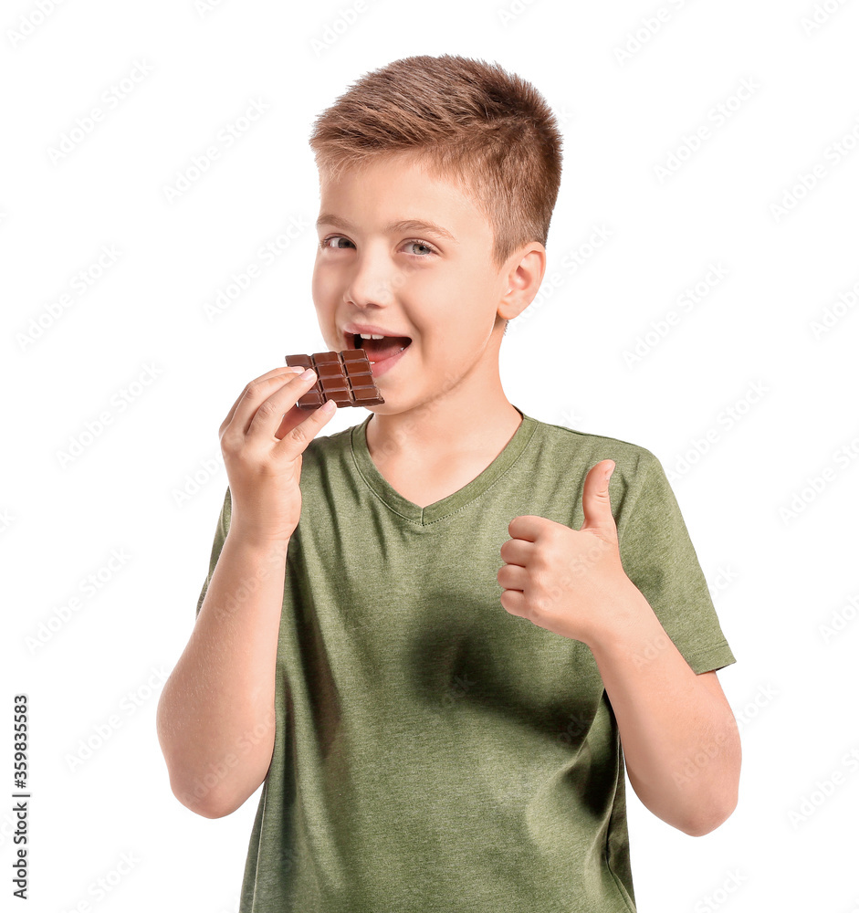 Cute little boy eating chocolate on white background