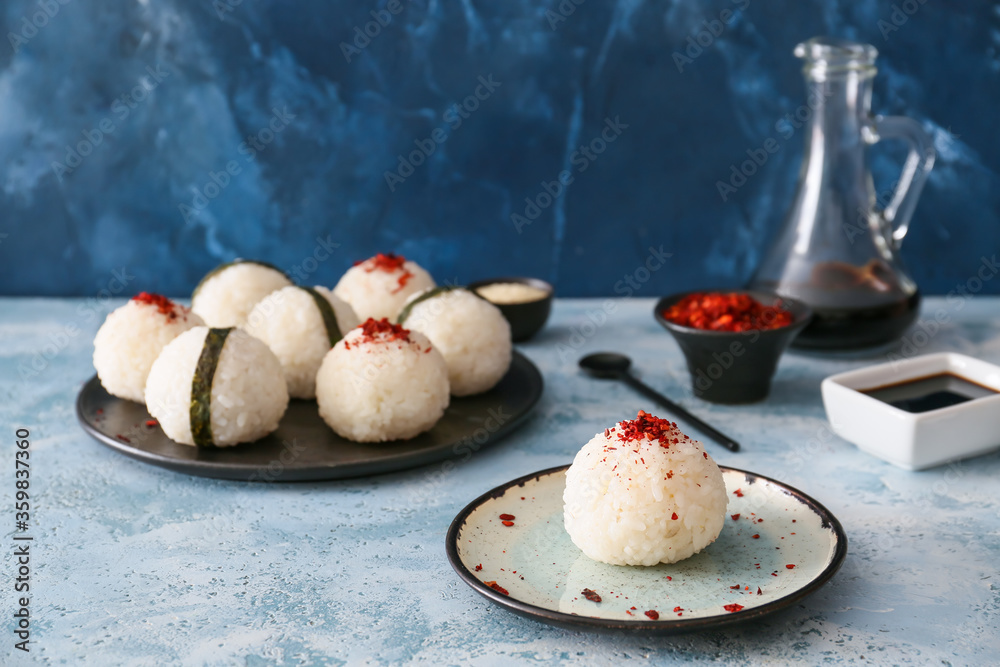 Traditional Japanese onigiri with spices on color background