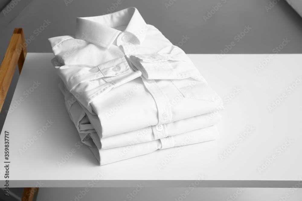 Stylish kid shirts on table in room