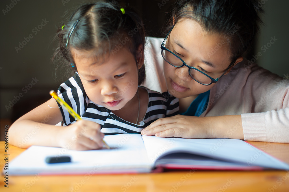 Happy family. Mother helps his little daughter do homework.