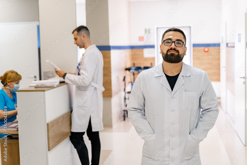 Doctor portrait on hospital corridor background. Doctor portrait in scrubs. Bearded doctor.