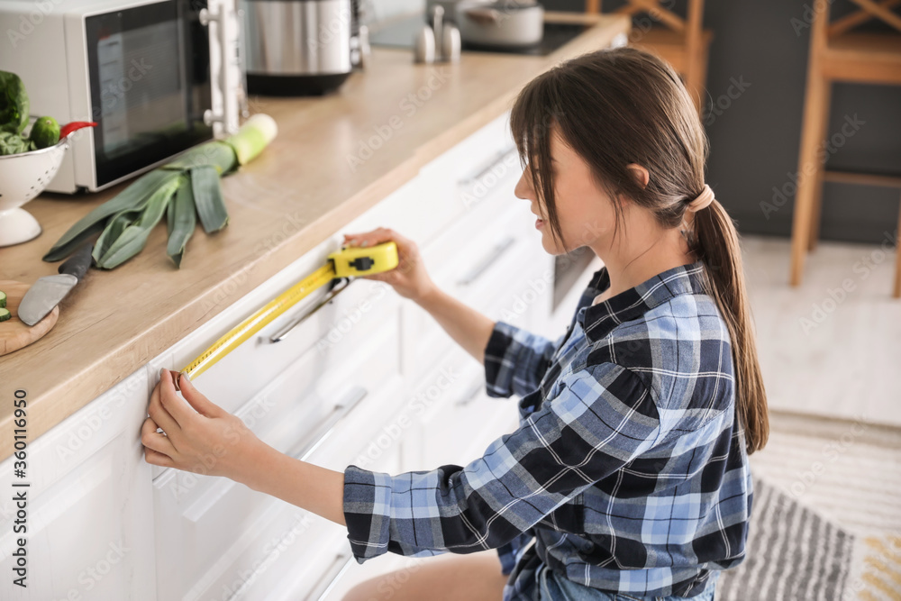 年轻女子在厨房测量家具