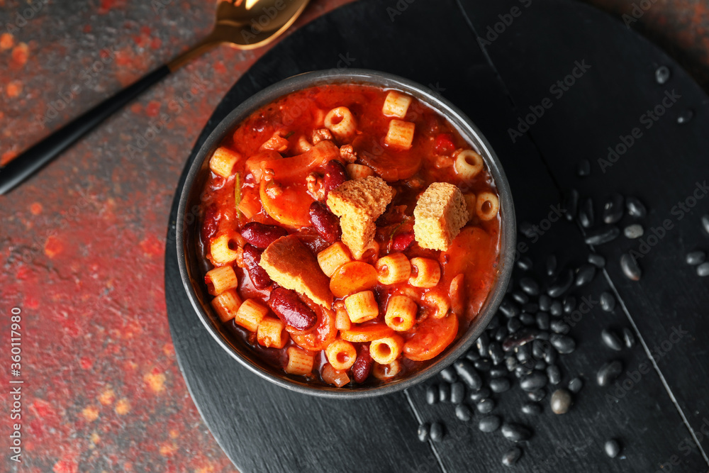 Bowl with tasty pasta and beans on color background