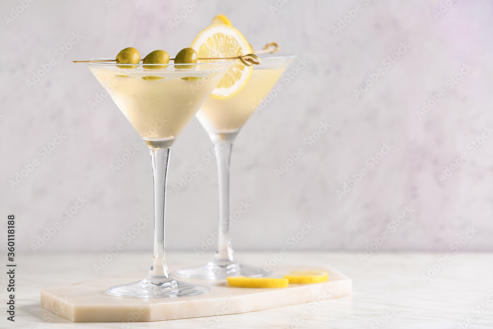 Glasses of tasty martini cocktail with olives on light background