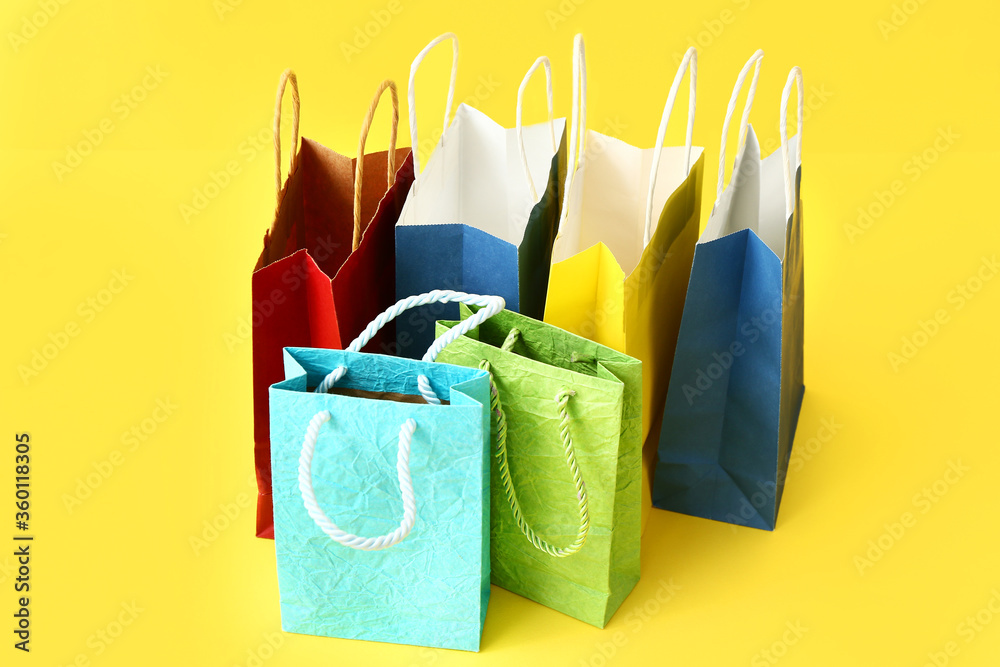 Paper shopping bags on color background