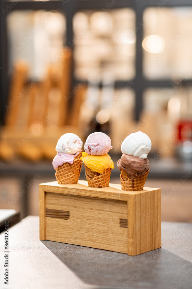 Ice cream in waffle cone with different flavors on the store counter, close-up