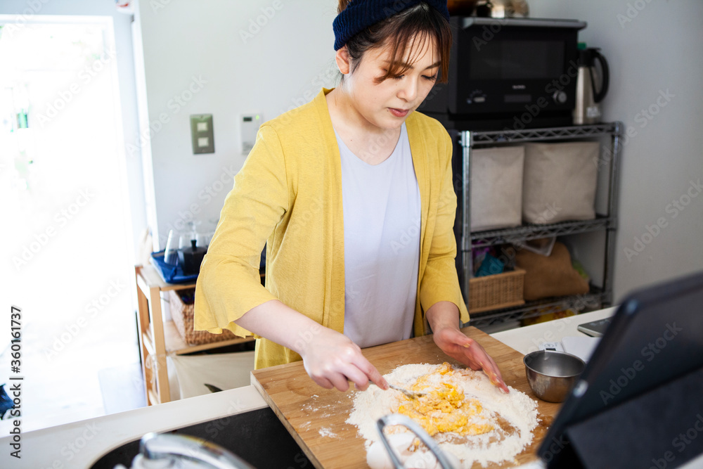 小麦粉と卵を混ぜる、料理中の女性