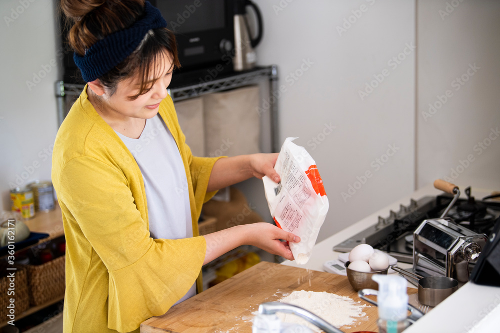 まな板に小麦粉を出す調理中の女性の手元