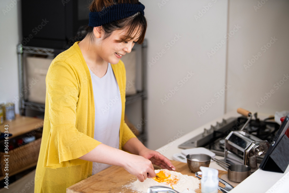 パスタの麺を作る料理中の女性
