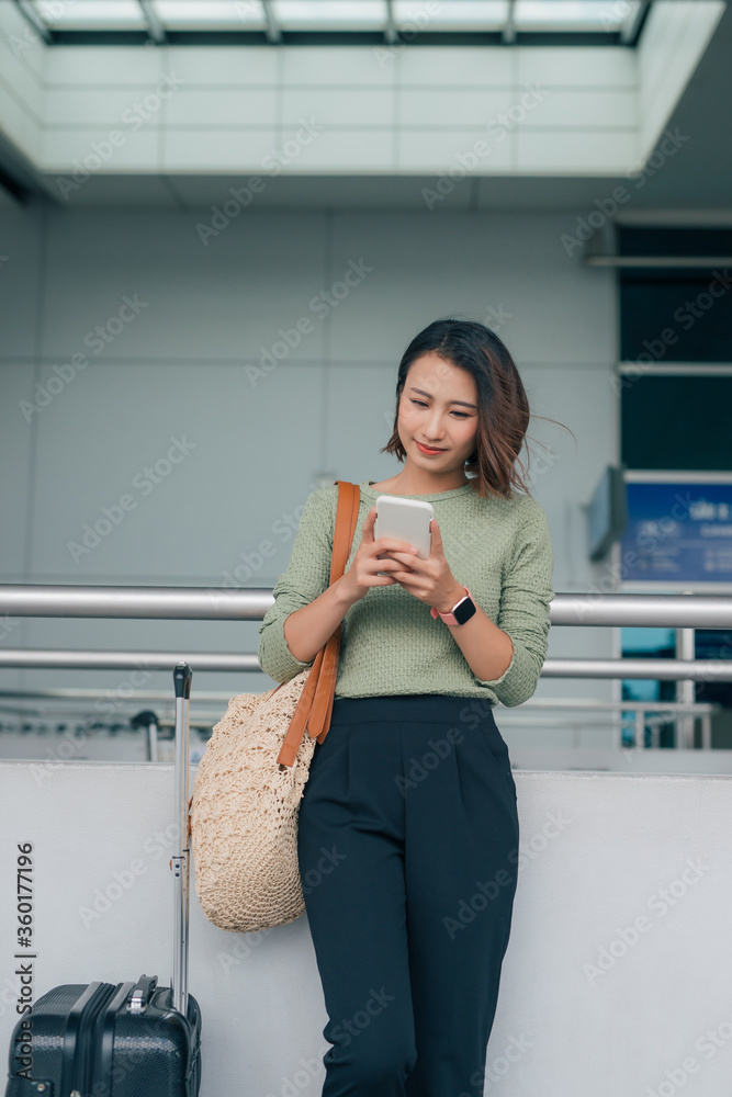 美丽的亚洲女商人使用智能手机在机场检查航班或在线办理登机手续，无线