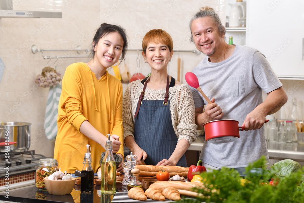 幸福的家庭，母亲、父亲和女儿在厨房做饭，一起做健康的食物，感觉很好