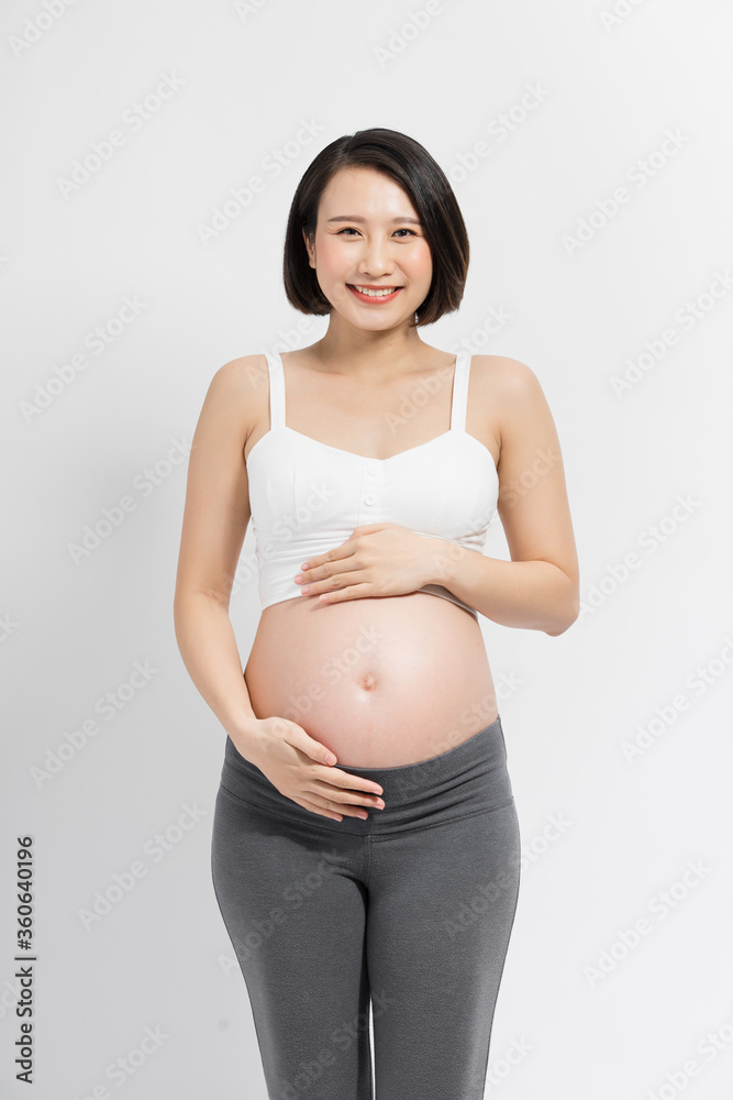 Beautiful pregnant woman touching her belly with hands on a white background.