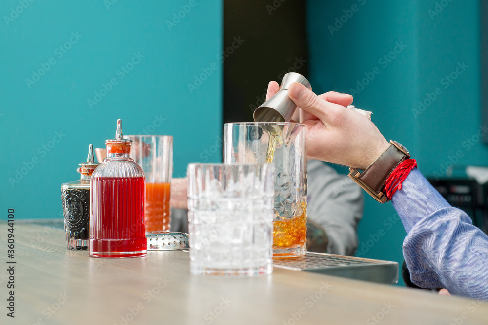 Bartender mixes a cocktail in a shaker and pours it. Making a cocktail. Mixology