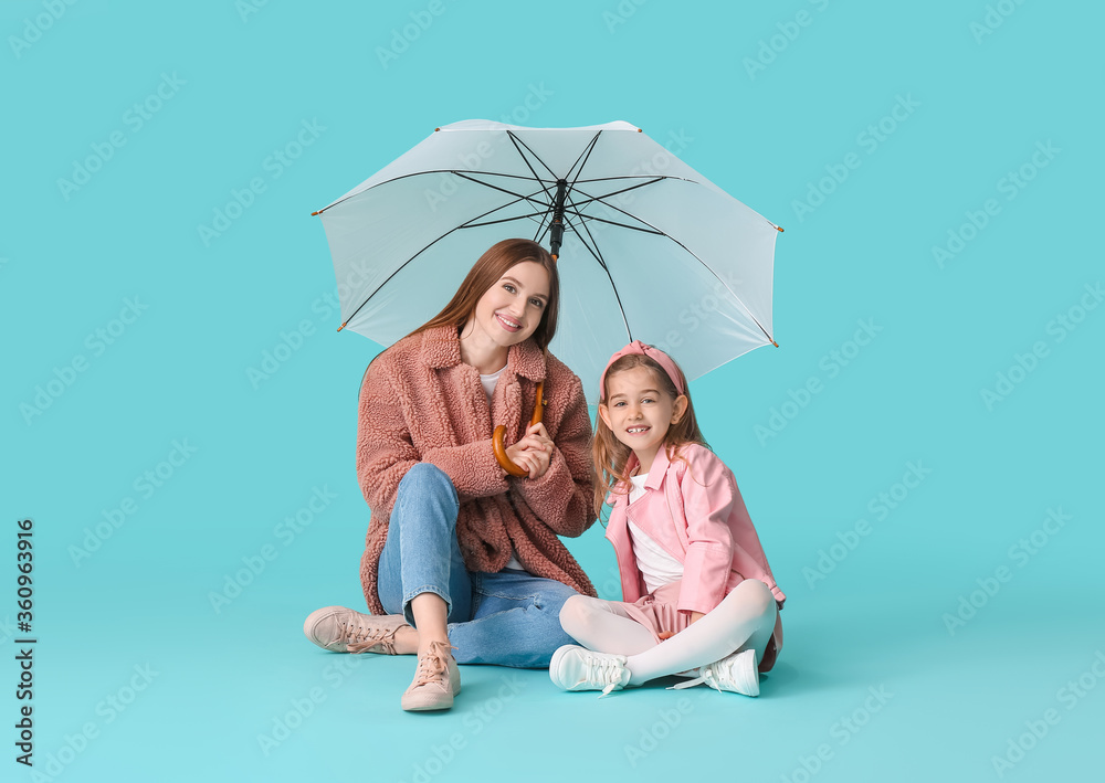 母亲和小女儿带着彩色背景的雨伞