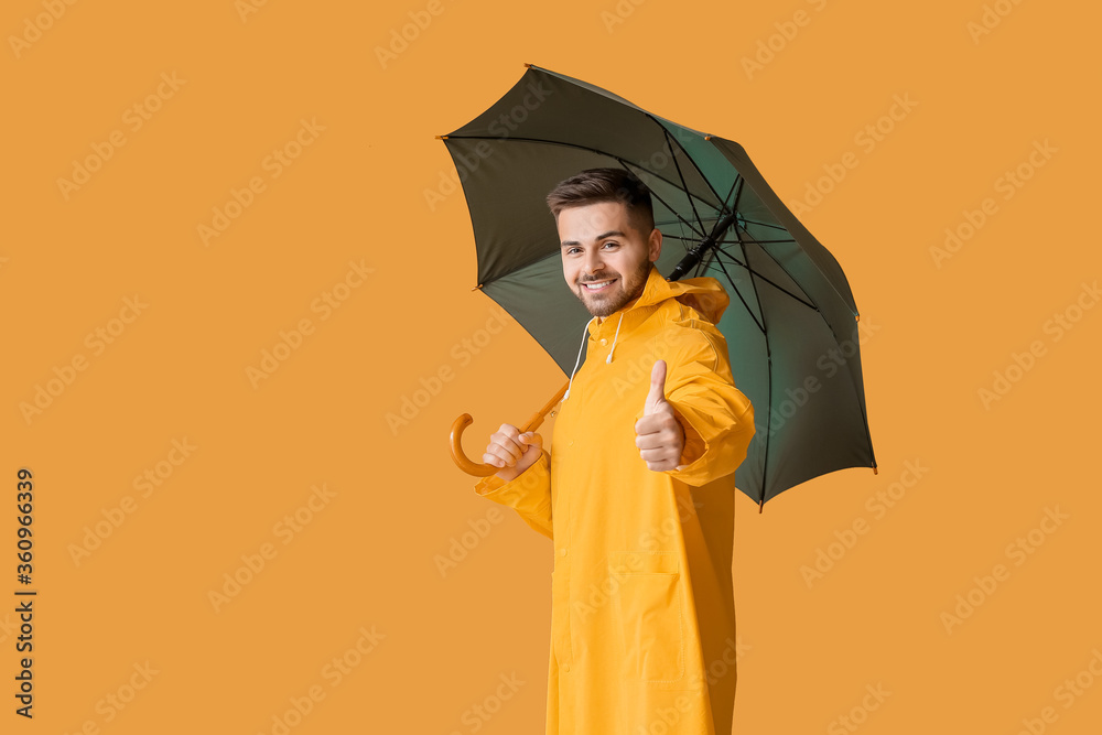 穿着雨衣、打着雨伞的年轻人在彩色背景上竖起大拇指