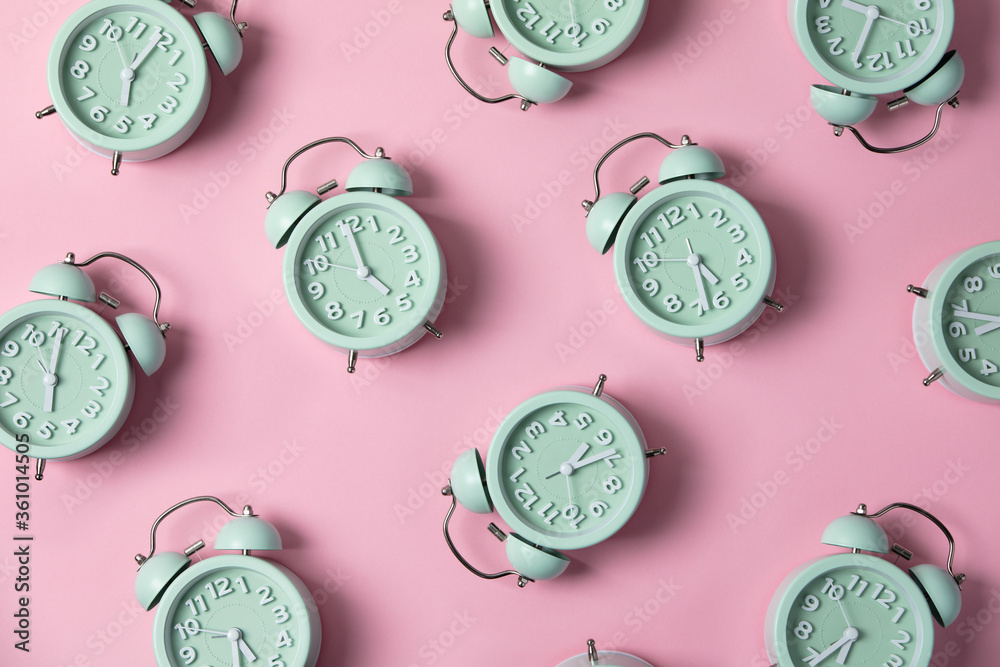 Creative layout of green alarm clocks on pastel pink background. Minimal concept.