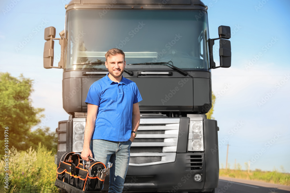 Male driver with tools near big truck outdoors