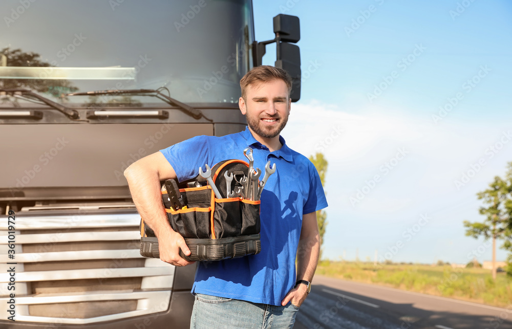 Male driver with tools near big truck outdoors