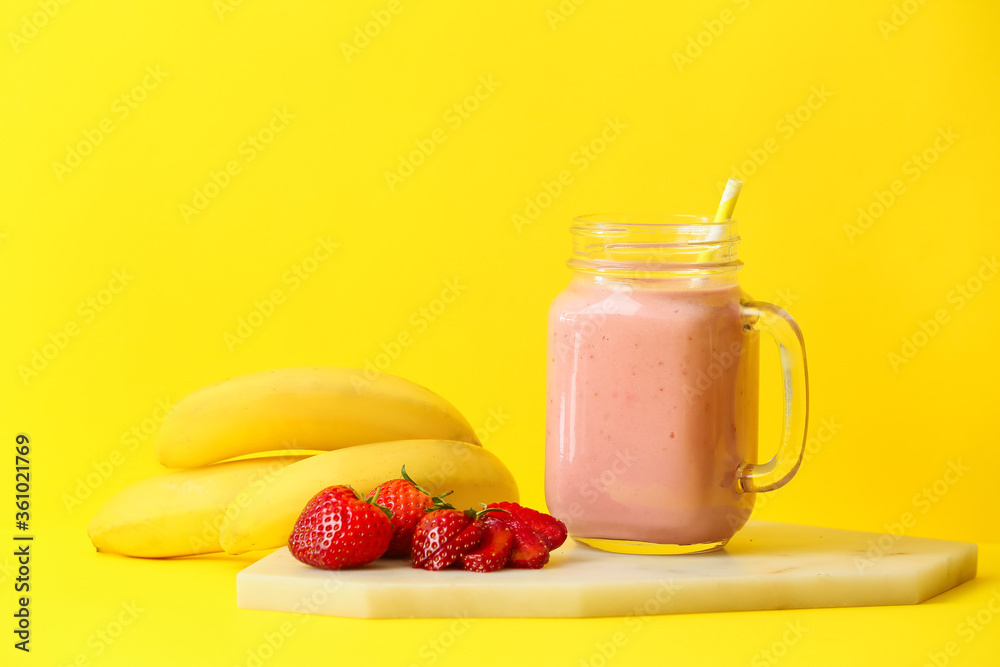 Mason jar of tasty strawberry smoothie on color background